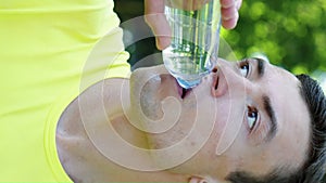 Vertical Screen: Man drinking water after workout in park