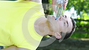 Vertical Screen: Man drinking water after workout in park