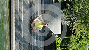 Vertical Screen: Yogi man meditating near pond in park