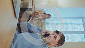 Vertical Screen: Young businessman talking on phone in cafe