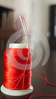 Vertical selective focus of a red spool of thread and a needle