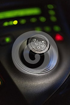 Vertical selective focus shot of the black gear shift knob of a car