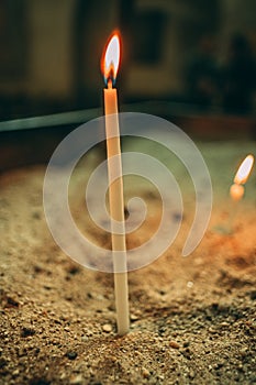 Vertical selective focus shot of lighting candle in church