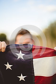 Vertical selective focus shot of a male holding the flag of the United States of America