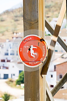 Vertical selective focus shot of round red Spanish warning sign against electricity on wooden pole