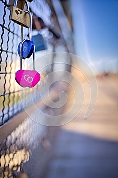 Vertical selective shot of heart-shaped love padlocks, locked to fence,concept of eternity love
