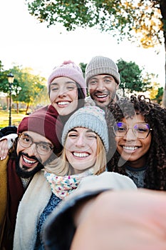 Vertical selfie portrait of a group of multiracial young people having fun in a travel trip on vacations. Front view of