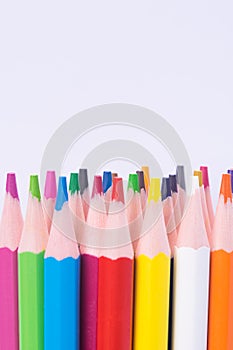 Vertical set of colored pencils, sharply sharpened, on top of a white background, there is a place for the inscription