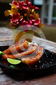 Vertical shallow focus closeup shot of grilled meat slices with lime in a black plate on a table