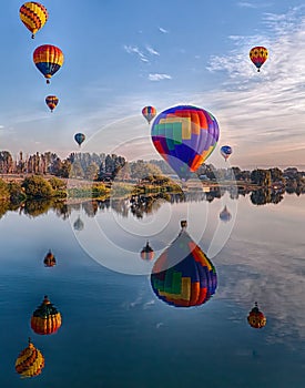 Vertical shot of air balloons in Prosser reflected in a river during the Washington balloon festival