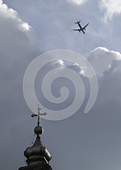 Vertical shot of an airplane flying over a church  steeple