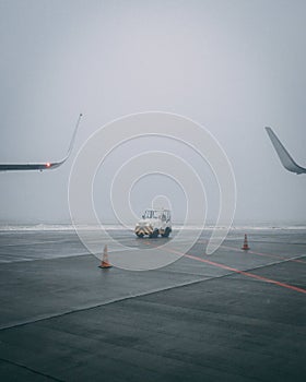 Vertical shot of an airplane runway on a moody day  with a little airport staff car