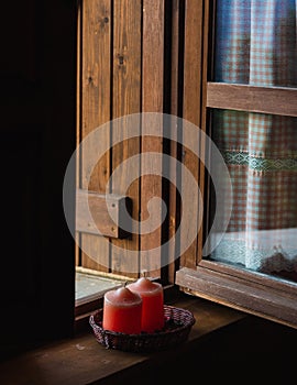 Vertical shot of aromatic candles in front of a beautiful wooden window