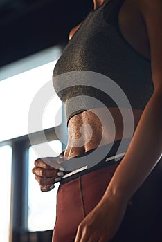 Vertical shot of athletic fitness woman wearing sports clothes showing perfect abs while working out at gym