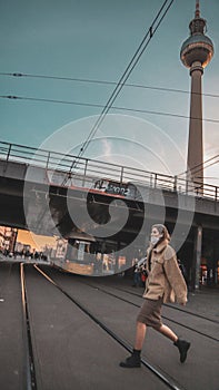 Vertical shot of an attractive woman crossing the street against the Berlin TV tower