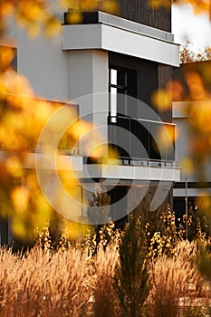 Vertical shot of a balcony of a beautiful modern house in front of a yard with trees and plants