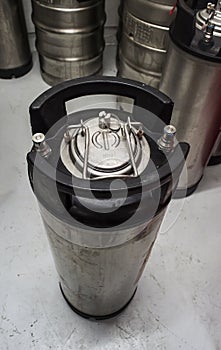 Vertical shot of a ball lock type keg with co2 input and beer output visible