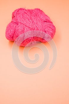 Vertical shot of a ball of pink yarn on an orange surface