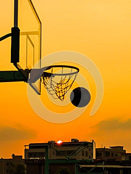 Vertical shot of a basketball net during the sunset