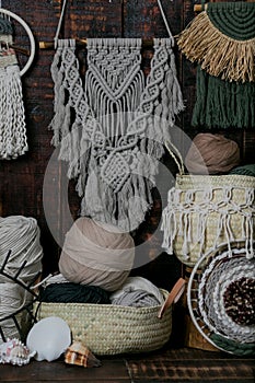 Vertical shot of baskets full of multicolored knitting wool balls and macrame hanging on the wall