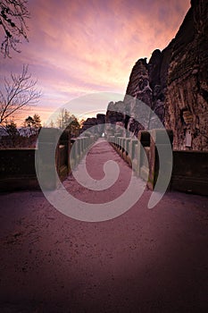 Vertical shot of Bastei bridge in Saxon Switzerland National Park under colorful susnet