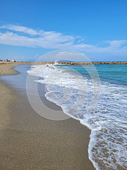 Vertical shot of the beachline with blue cloudy sky