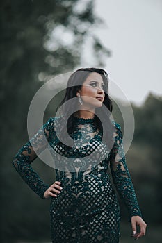 Vertical shot of a beautiful Bosnian Caucasian woman wearing a formal dress, posing outdoors