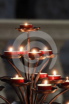 Vertical shot of beautiful candles on a golden candle holder for the worshipers of the church