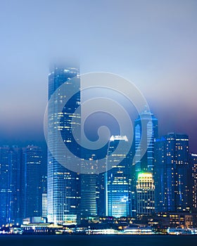 Vertical shot of beautiful cityscape with illuminated building enveloped in fog in Hong Kong, China