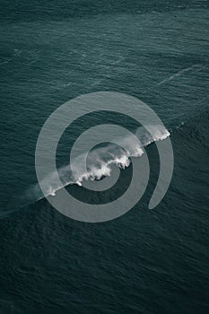 Vertical shot of beautiful colliding strong ocean waves on a cloudy day