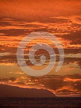 Vertical shot of a beautiful red sunset over the ocean at the Honululu city in Hawaii islands