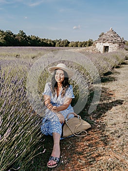 Vertical shot of a beautiful young Caucasian woman in a straw hat in a lavender field