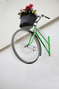 Vertical shot of a bicycle with flowers decorating the wall of one of the buildings of the city