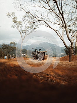 Vertical shot of a bicycle next to a wooden table with mountains in the background