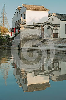 Vertical shot of a big private house with a balcony reflected on the water of a swimming pool