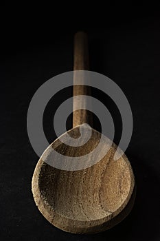 Vertical shot of a big wooden spoon isolated on black background