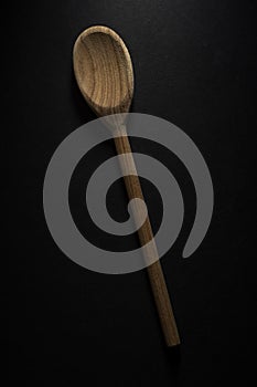 Vertical shot of a big wooden spoon isolated on black background