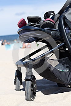 Vertical shot of a black baby stroller on a white sandy beach on sunny day