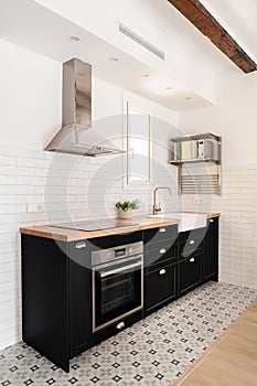 Vertical shot black kitchen island with drawers stove and convection cooker and modern appliances in scandinavian style