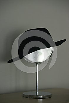 Vertical shot of black women's hat on the make-up mirror on the grey background