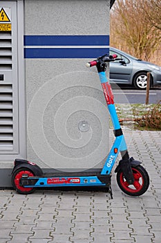 Vertical shot of blue Dott brand rental electric scooter in leaning against a wall in Poznan, Poland