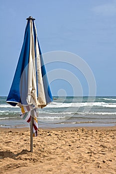 Vertical shot of a blue and white beach umbrella planted in the sand in Gandia, Valencia, Spain
