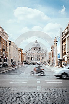 Vertical shot of a blurred motorbiker and the St. Peter`s Basilica in Vatican City