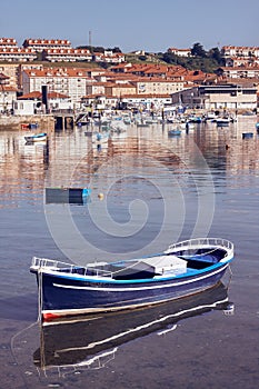 Vertical shot of a boat floating in water in front of a coast town