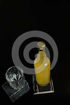 Vertical shot of a bottle of orange juice, lemonade, alcoholic beverage and an empty glass standing on black wooden table