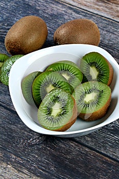 Vertical shot of a bowl filled with slices of fresh kiwi on a wooden surface