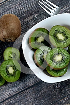 Vertical shot of a bowl filled with slices of fresh kiwi on a wooden surface