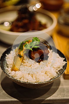 Vertical shot of a bowl of rice with meat and vegetables on it in a Chinese way