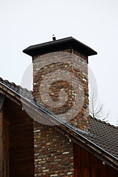 Vertical shot of a brick chimney with a cloudy sky in the background photo