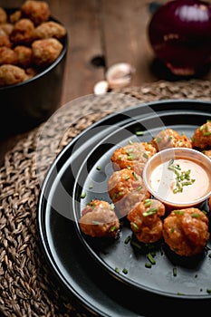 Vertical shot of Buffalo cauliflower bites served on a black plate with a sauce at a restaurant